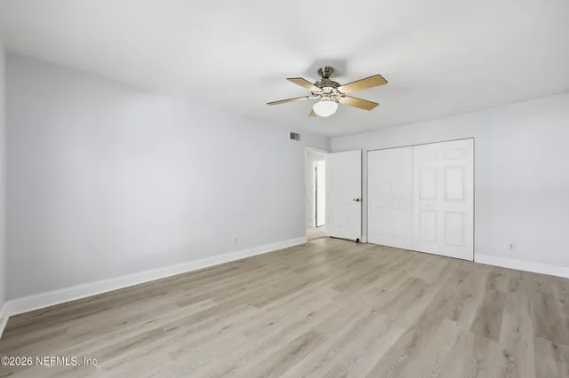 an empty room with wooden floor closet and fan
