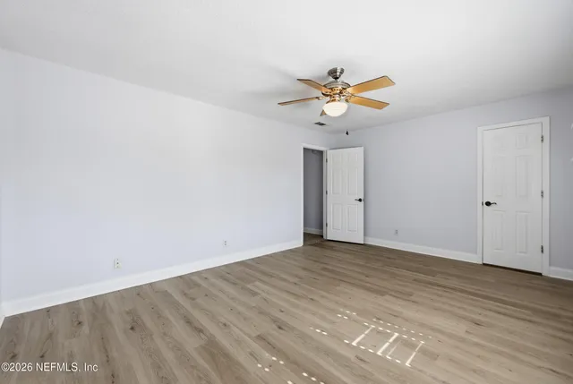 a view of a room with wooden floor and a ceiling fan
