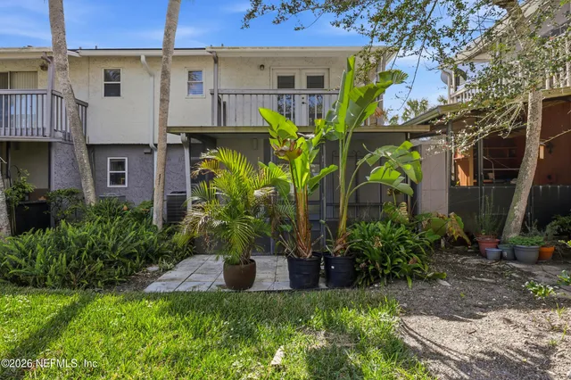 a front view of a house with a yard and potted plants