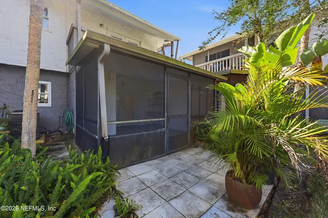 a backyard of a house with potted plants and large tree