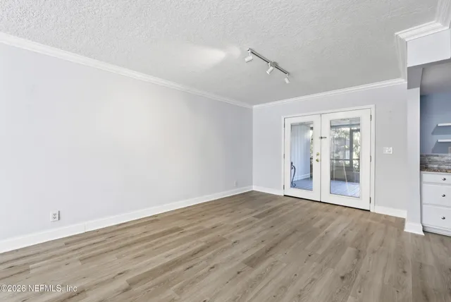 a view of an empty room with wooden floor and a window