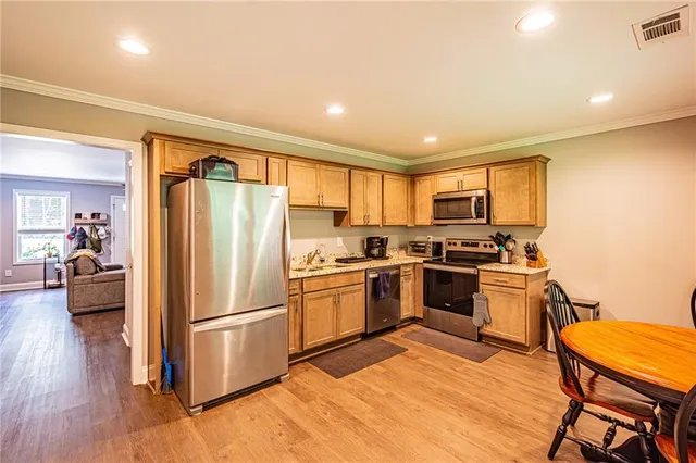 a kitchen with a refrigerator a stove top oven a sink dishwasher and white cabinets with wooden floor