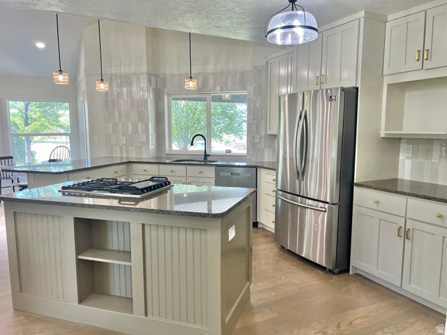812 East Bates Cyn Road Tooele, UT 84074 - Photo 24 of 144 Bright kitchen featuring a central island with an integrated cooktop, granite countertops, stainless steel appliances, white shaker cabinetry with gold hardware, and wood-finish flooring