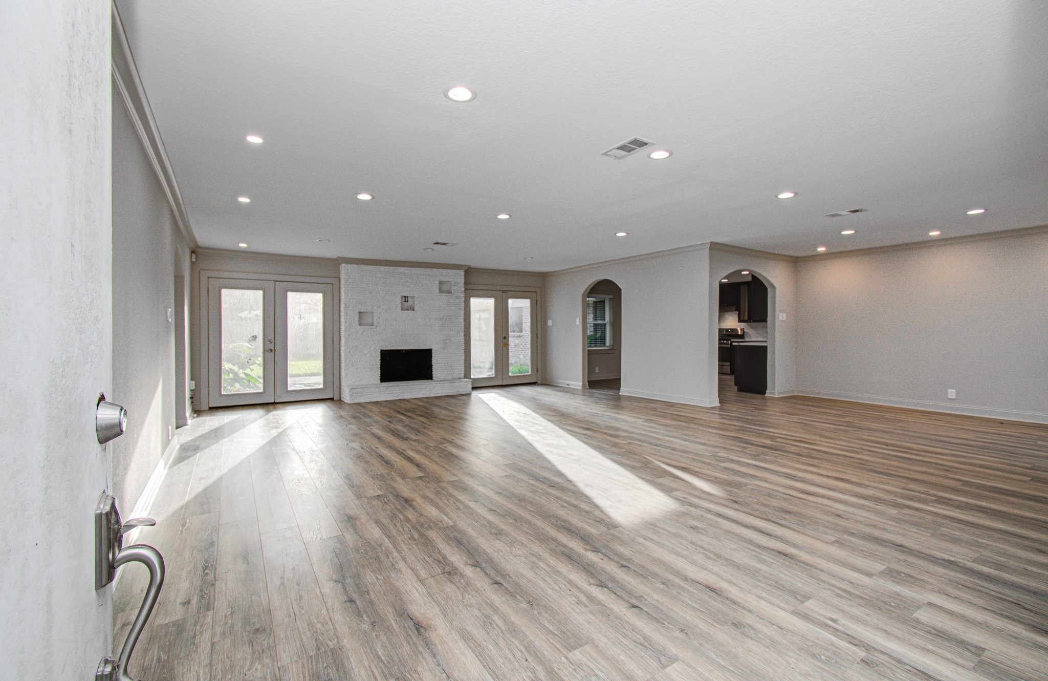 1801 Benbow Way Houston, TX 77080 - Photo 4 of 32 This spacious living area features elegant wood flooring, a white brick fireplace, and ample natural light from large glass doors. It's open to the kitchen area, creating a seamless flow for entertaining and daily living.