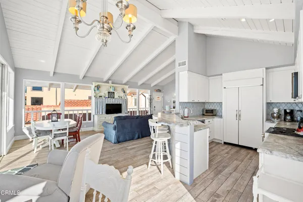 a living room with stainless steel appliances kitchen island granite countertop furniture a fireplace a flat screen tv and a window