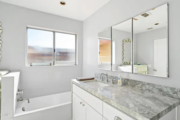 a bathroom with a granite countertop sink mirror and a bathtub