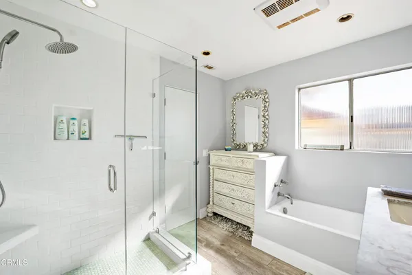 a bathroom with a tub shower vanity and a sink