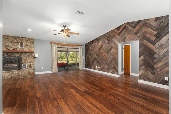 a view of an empty room with wooden floor and a fireplace