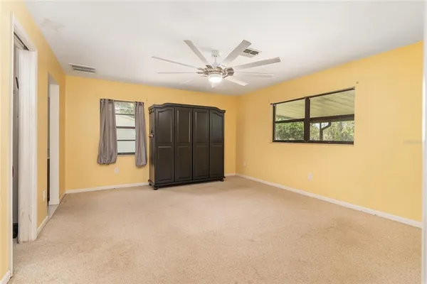 an empty room with windows and ceiling fan