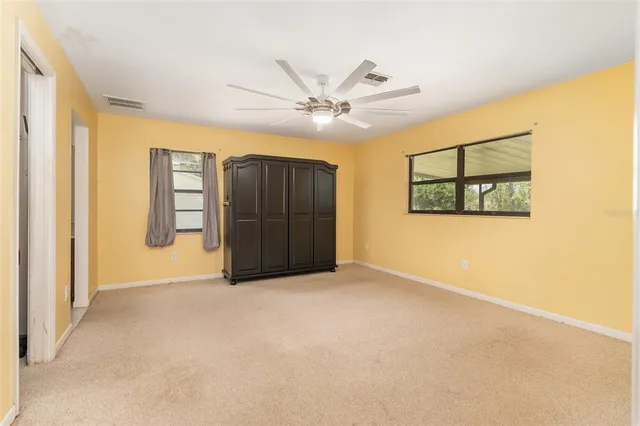 an empty room with windows and ceiling fan
