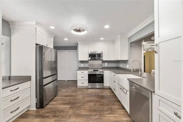 a large kitchen with a large counter top stainless steel appliances and cabinets