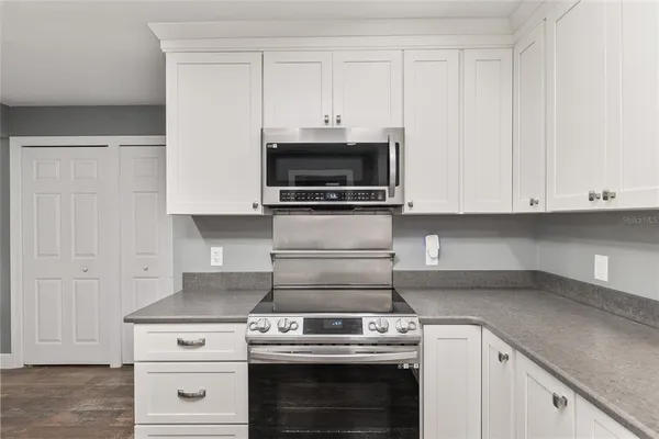 a kitchen with stainless steel appliances granite countertop white cabinets and a stove a oven with white countertops