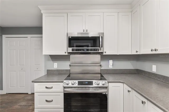 a kitchen with stainless steel appliances granite countertop white cabinets and a stove a oven with white countertops