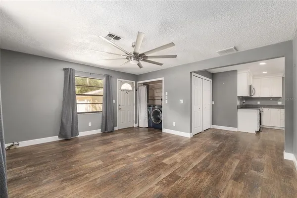 a view of an empty room with window and wooden floor
