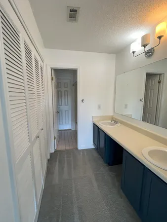a spacious bathroom with a double vanity sink a large mirror and a bathtub