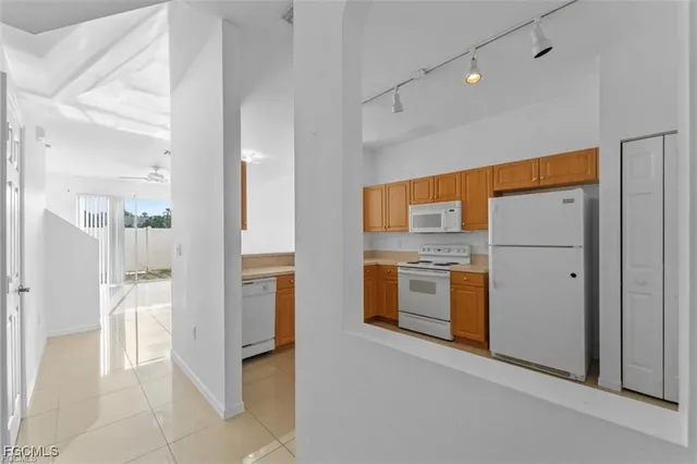 an empty room with a kitchen and a chandelier fan