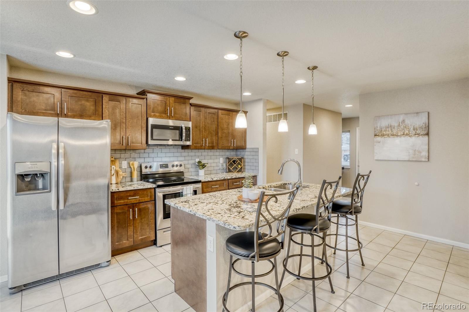 2682 South Quintero Way Aurora, CO 80013 - Photo 5 of 25 a kitchen with stainless steel appliances granite countertop a stove a refrigerator a oven a sink with a dining table and chairs