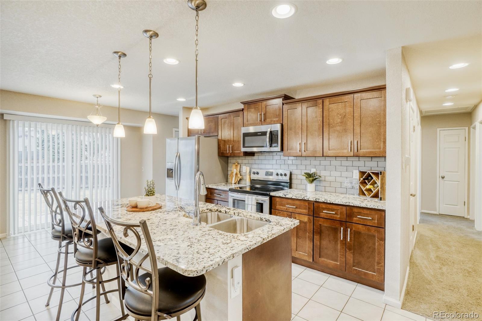 2682 South Quintero Way Aurora, CO 80013 - Photo 7 of 25 a kitchen with granite countertop a table chairs microwave and sink