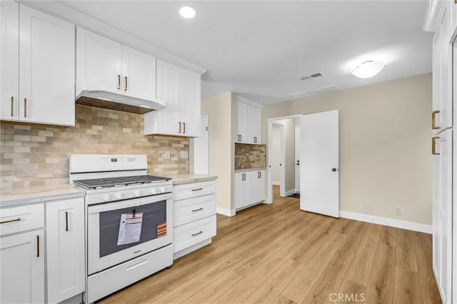 a kitchen with stainless steel appliances white cabinets and a stove top oven