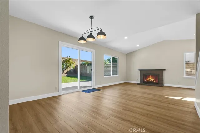 a view of an empty room with wooden floor fireplace and a window