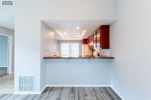 an empty room with wooden floor chandelier and windows