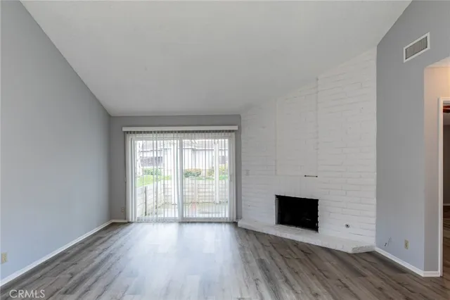 a view of a livingroom with wooden floor and a kitchen