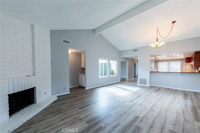 an empty room with wooden floor chandelier and windows
