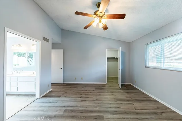 an empty room with wooden floor and a ceiling fan