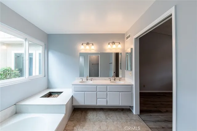 a bathroom with a tub a sink and a window