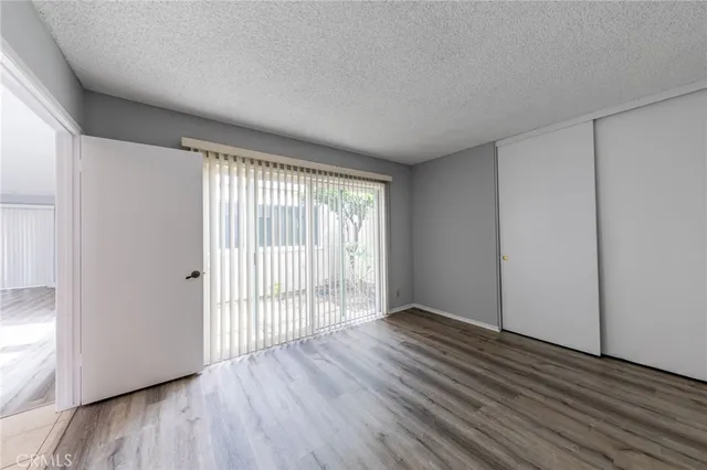 a view of an empty room with wooden floor and closet