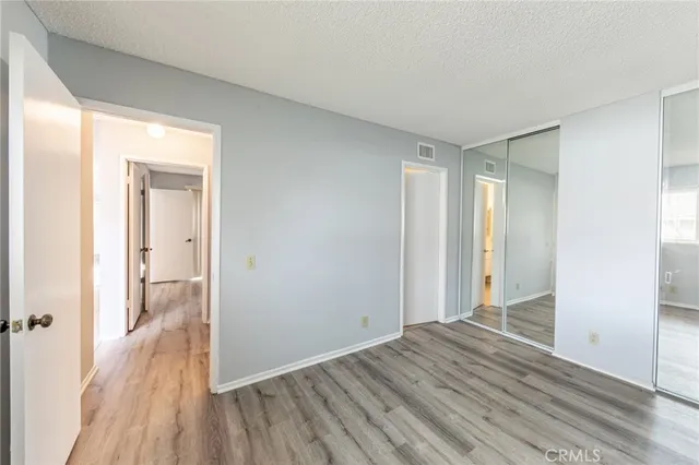 an empty room with wooden floor cabinet and windows