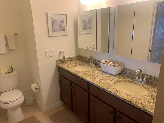 a bathroom with a granite countertop sink a mirror and a toilet