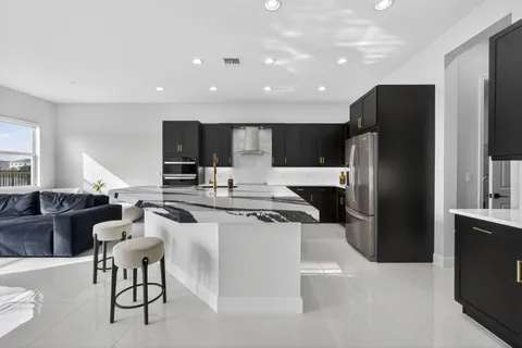 a kitchen with stainless steel appliances kitchen island granite countertop a refrigerator a stove a sink a microwave a dining table and chairs