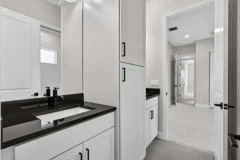 a bathroom with a granite countertop sink a toilet a large mirror and shower