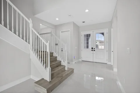 a view of a hallway with white walls and stairs