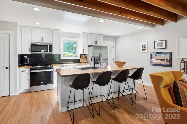 a kitchen with stainless steel appliances granite countertop a stove top oven a sink dishwasher a dining table and chairs with wooden floor