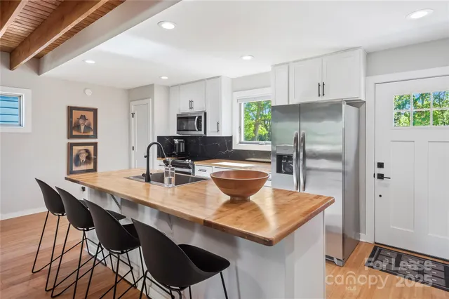 a kitchen with stainless steel appliances granite countertop a dining table chairs and refrigerator