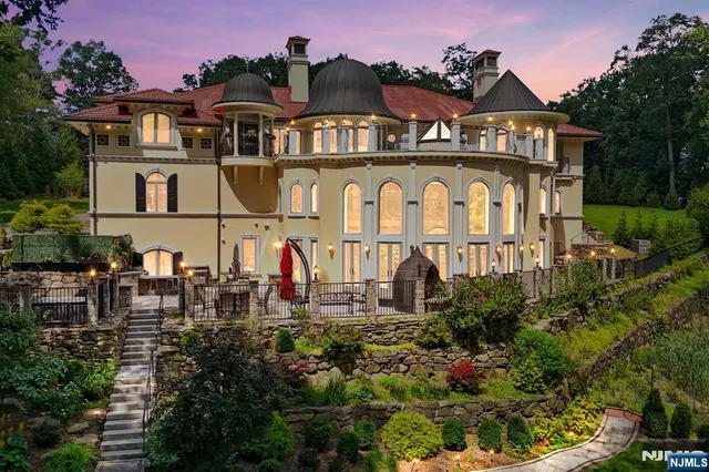 a view of a white house with large windows and a yard table and chairs