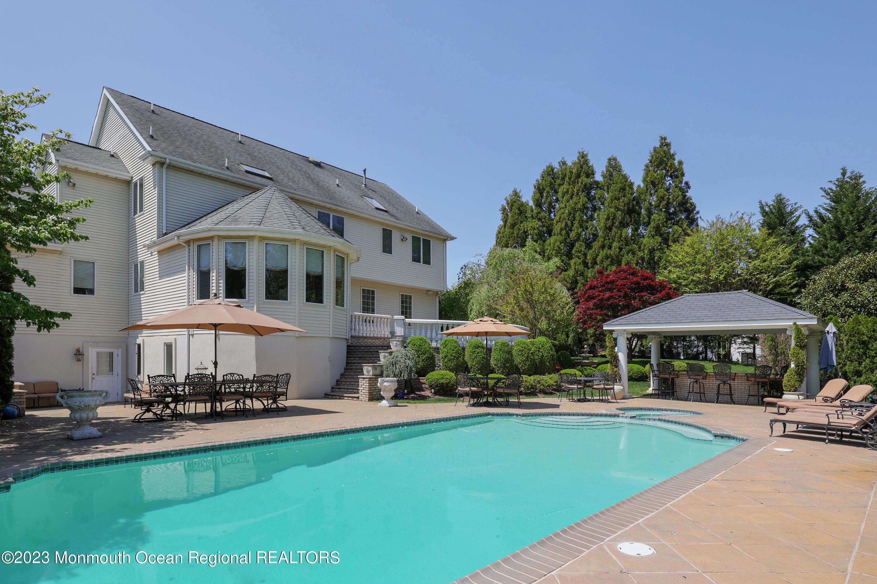 8 Old Stable Way Colts Neck, NJ 07722 - Photo 36 of 45 a view of a swimming pool with lawn chairs under an umbrella