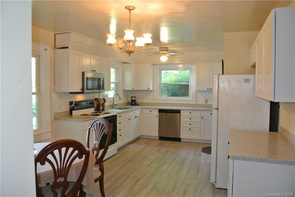 553 Chimney Rock Road Rutherfordton, NC 28139 - Photo 10 of 12 a kitchen with a refrigerator a sink dishwasher a stove and a dining table with wooden floor