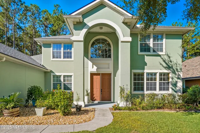 a view of a brick house with a large windows and flower plants