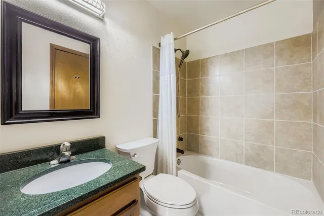 a bathroom with a granite countertop sink toilet mirror and bathtub