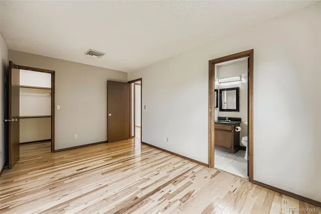 a view of an empty room with cabinet and wooden floor