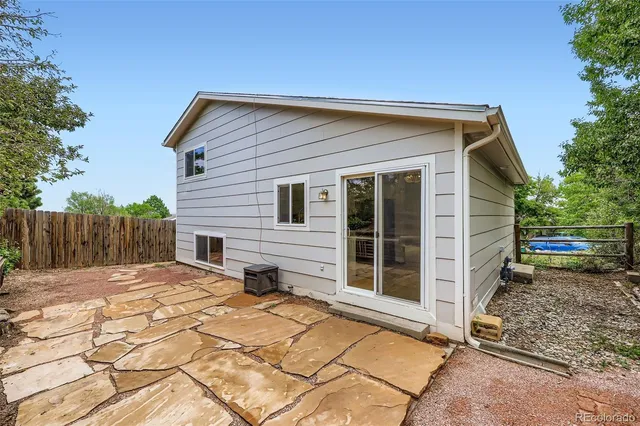 a backyard of a house with large trees and wooden fence