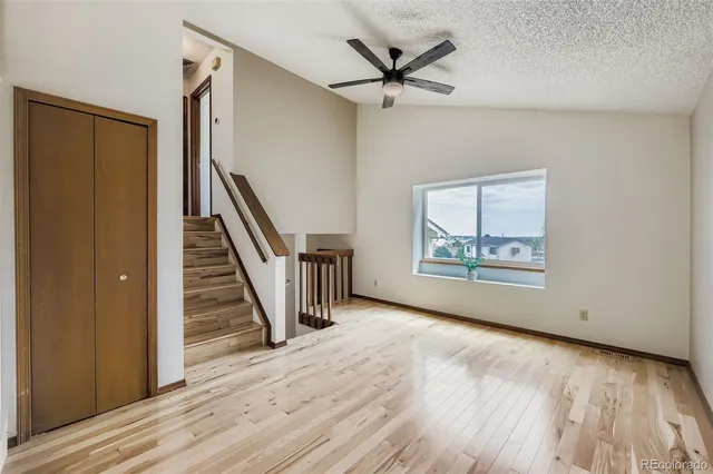 a view of an empty room with wooden floor and stairs