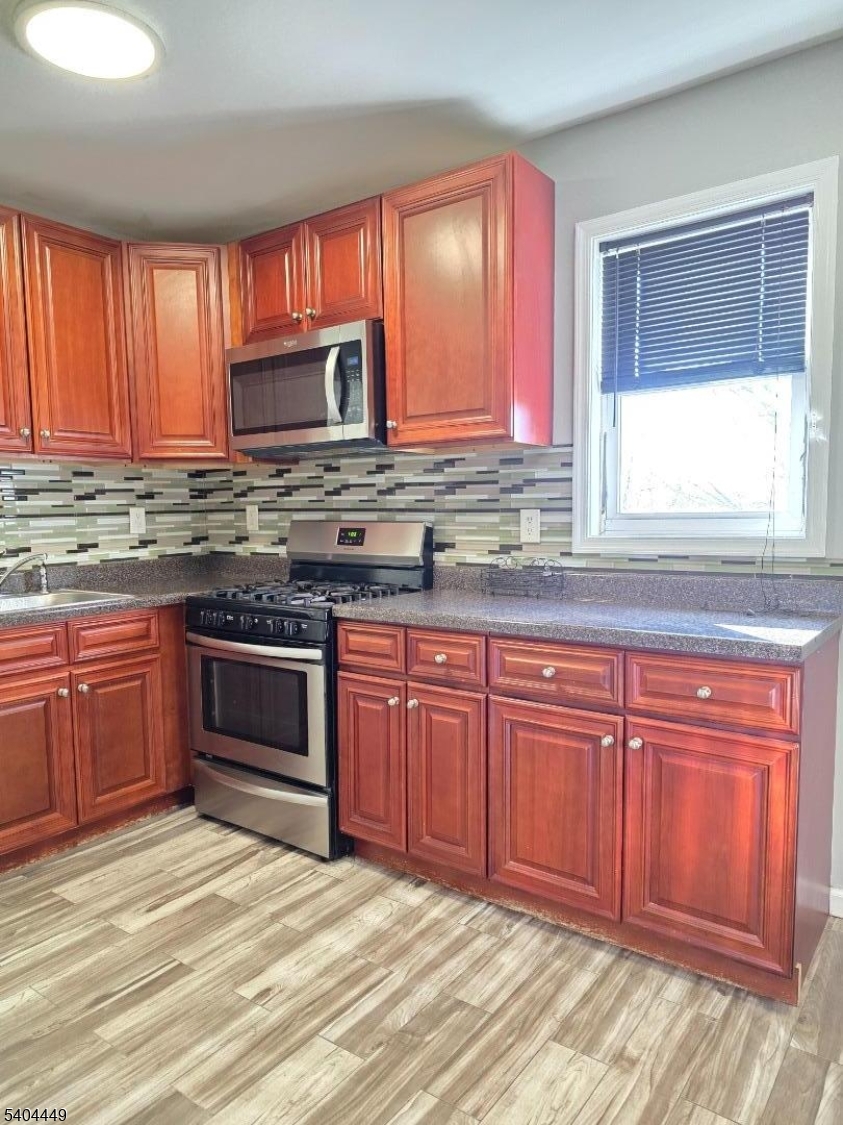 a kitchen with stainless steel appliances granite countertop wooden cabinets a sink and a stove