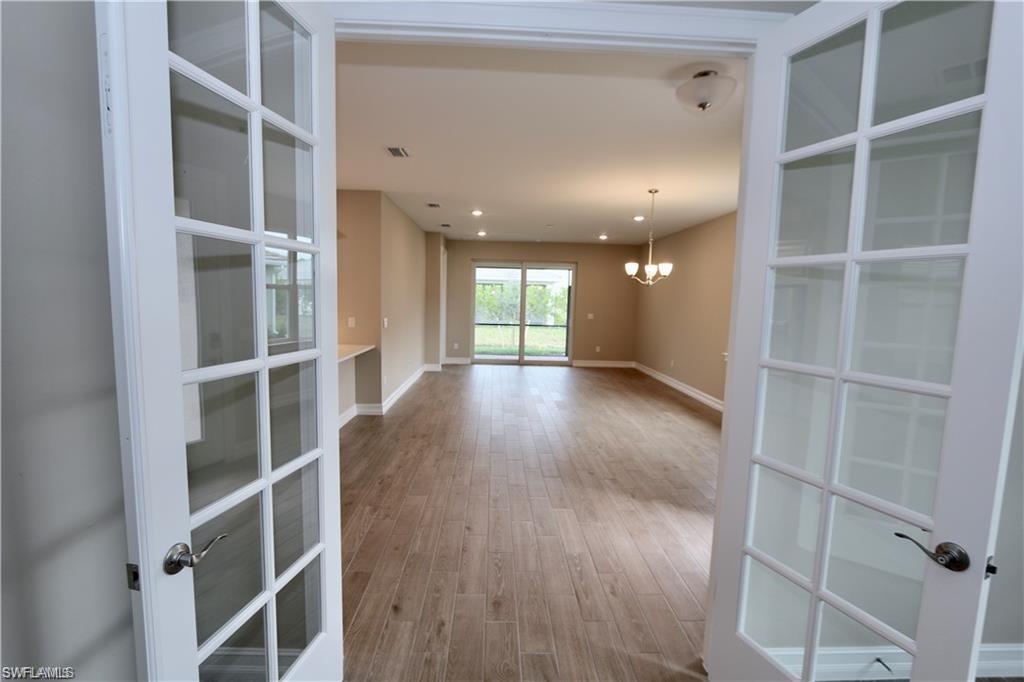 1063 Enbrook Loop Naples, FL 34114 - Photo 10 of 26 Spare room with a chandelier, light wood-style flooring, french doors, and recessed lighting