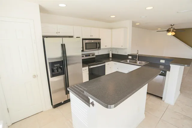 a kitchen with granite countertop a refrigerator a sink a stove a microwave and island