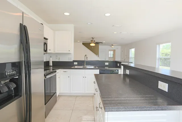 a large kitchen with stainless steel appliances kitchen island granite countertop a refrigerator a sink a stove and white cabinets