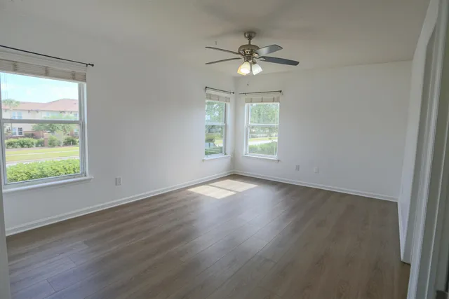 a view of empty room with wooden floor and fan